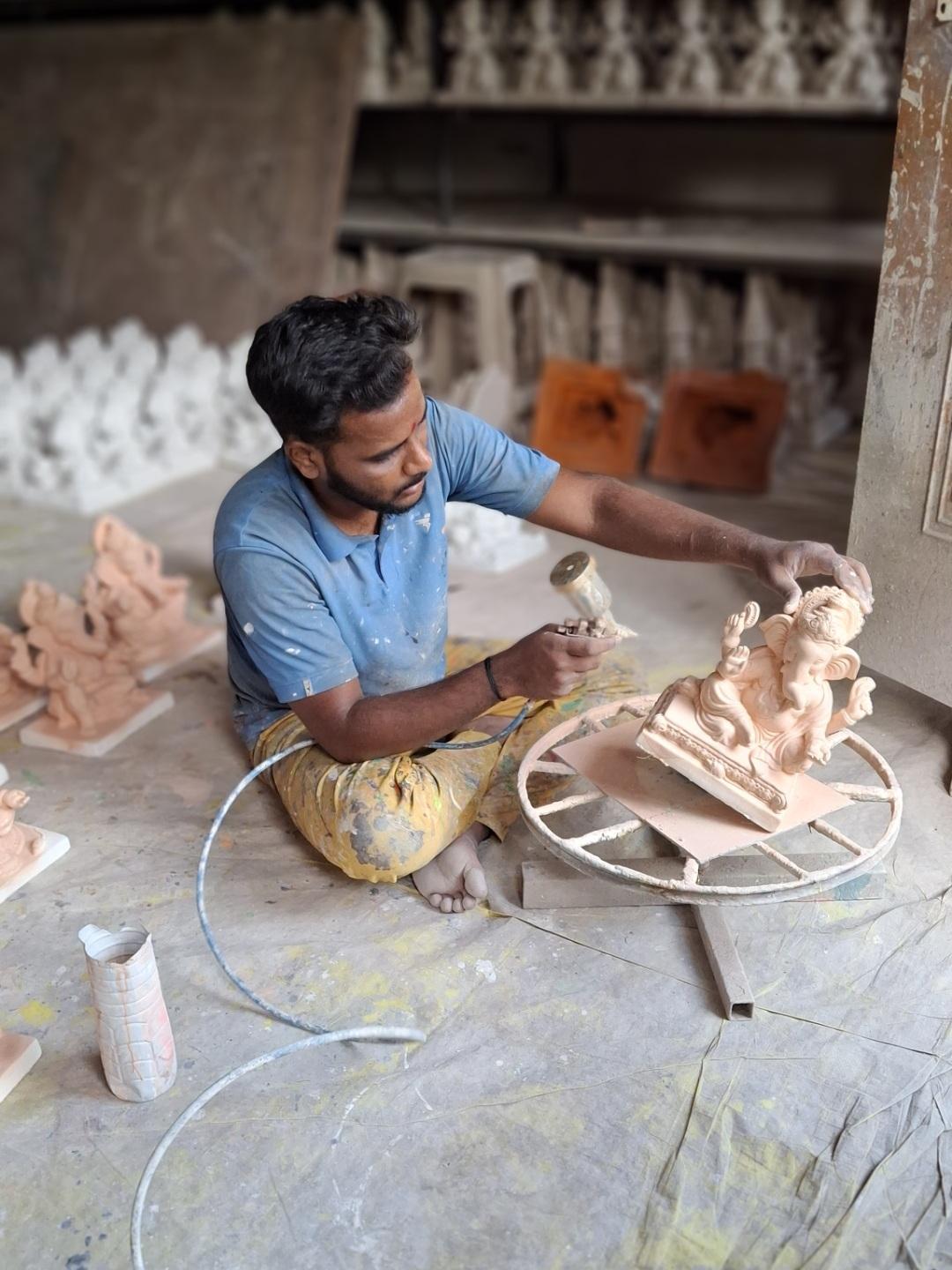 An artisan spray painting the murtis. (Source: CKA Archives)