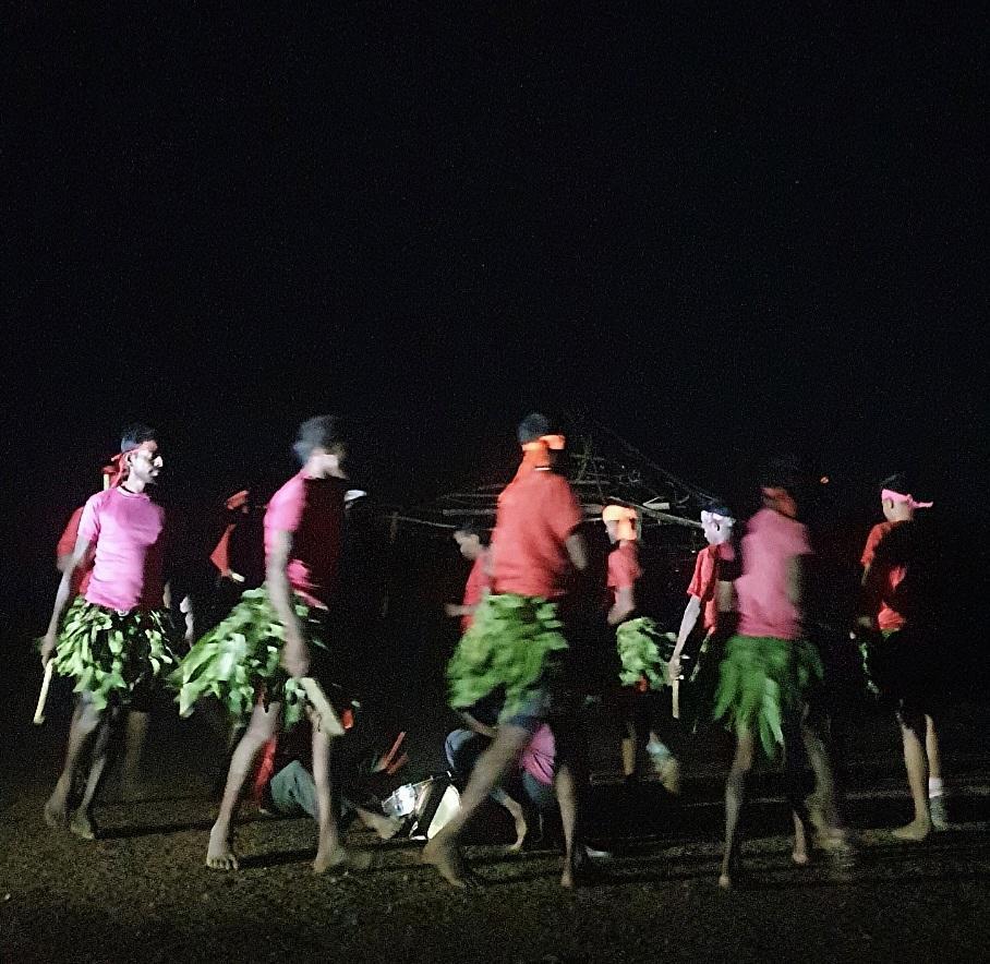 Men, dressed in traditional attire with skirts made of leaves hold dandiyas as they dance in circles. (Source: CKA Archives)
