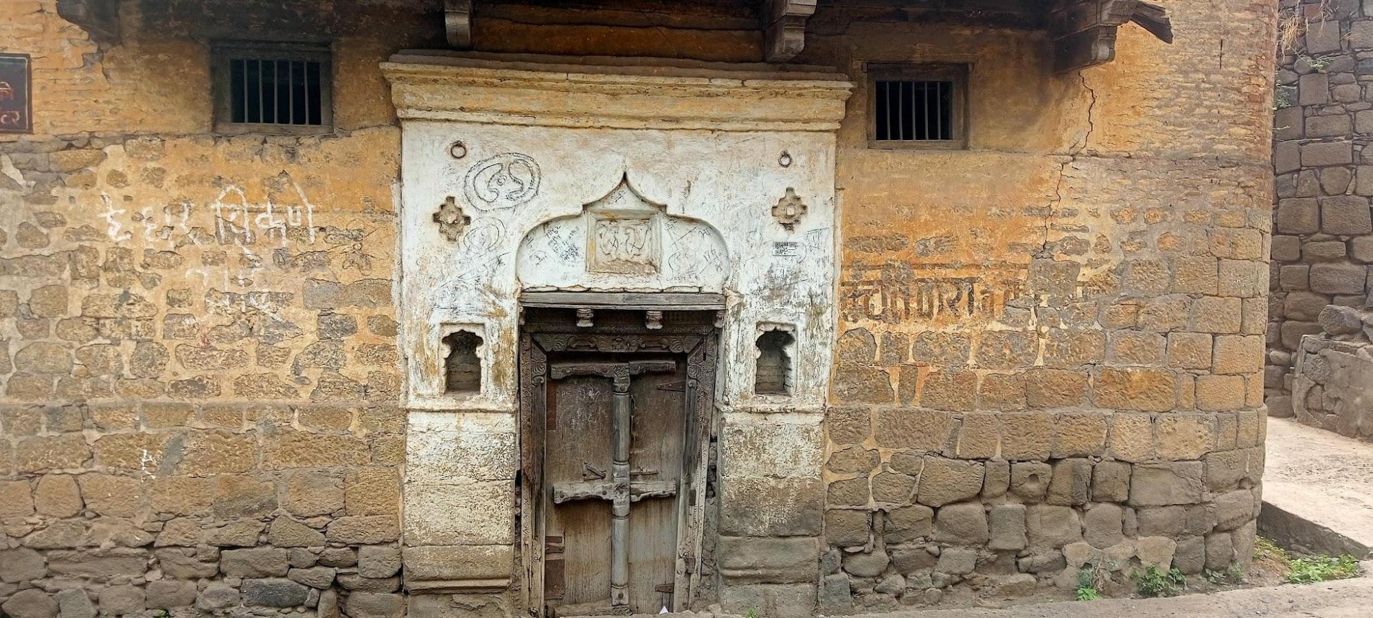 The intricately designed entrance door of an old structure, showcasing traditional stone masonry and detailed carvings. (Source: CKA Archives)