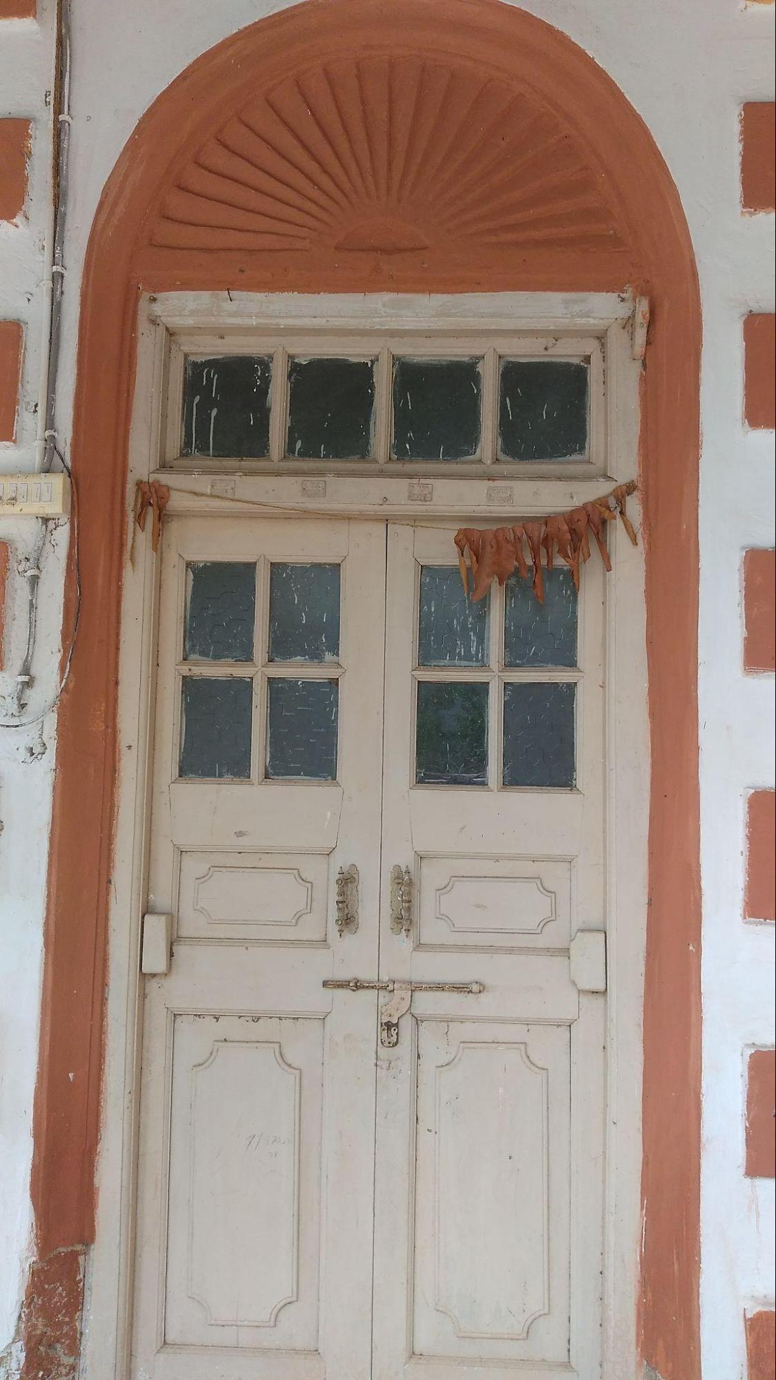 A double-leaf door set in a niche with glass panels and ray-like arch designs. (Source: CKA Archives)