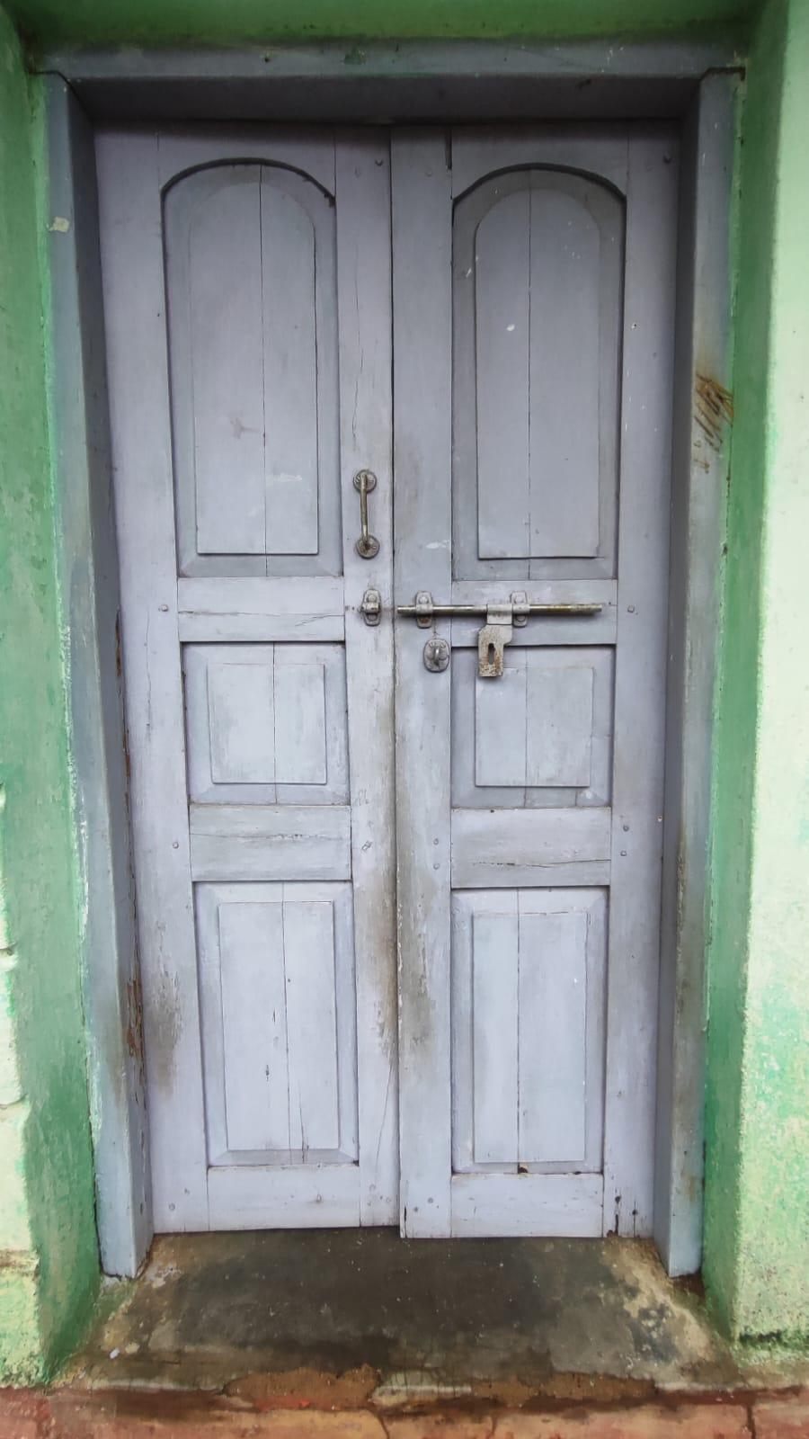A double-leaf door (two-panel door) painted in a white color, with each leaf divided into three  panels with some shaped in arches, rectangles, and squares. (Source: CKA Archives)