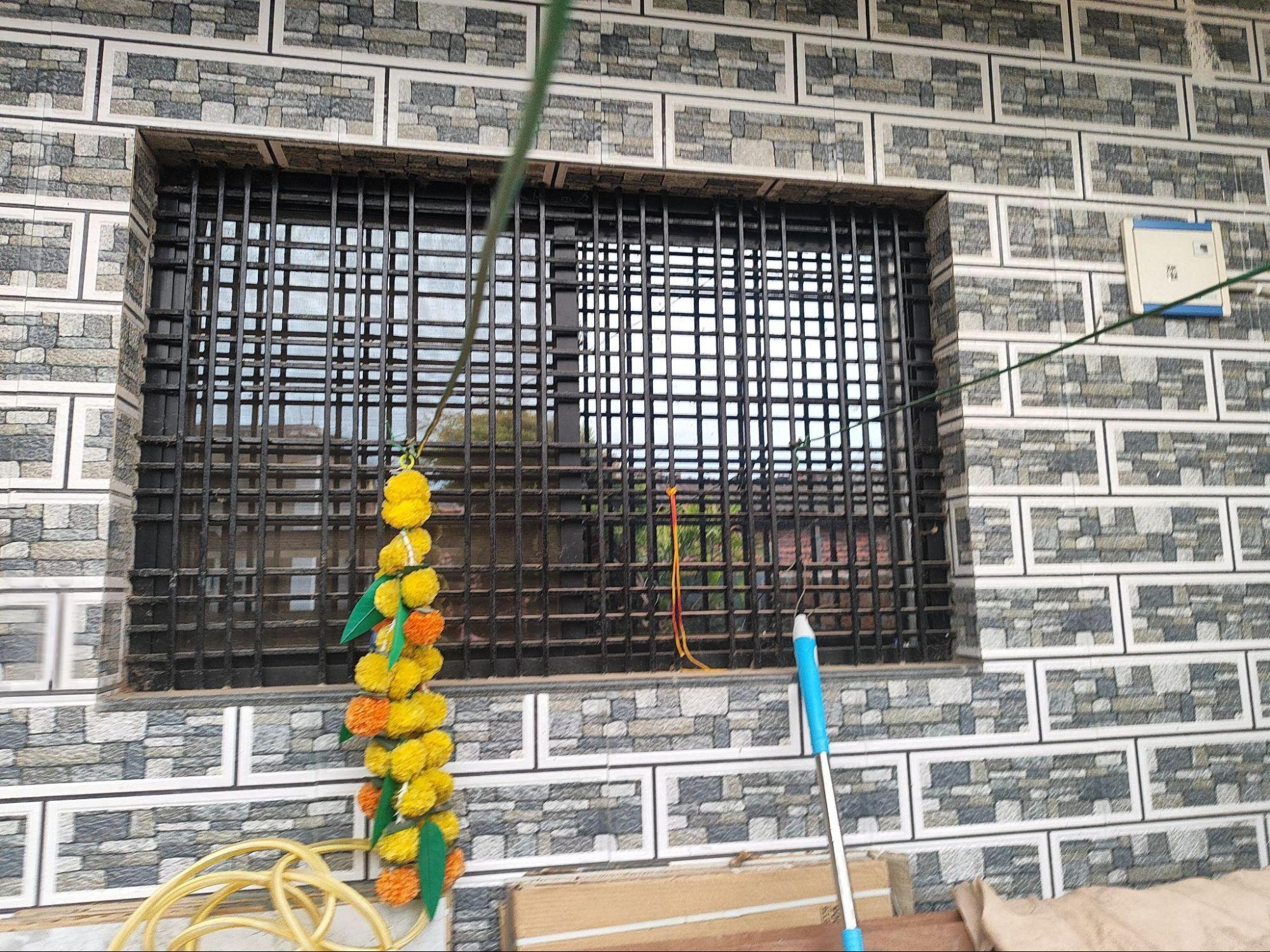 Metal grills on windows with a webbed design. Notice the stone cladding within which this window is placed. (Source: CKA Archives)