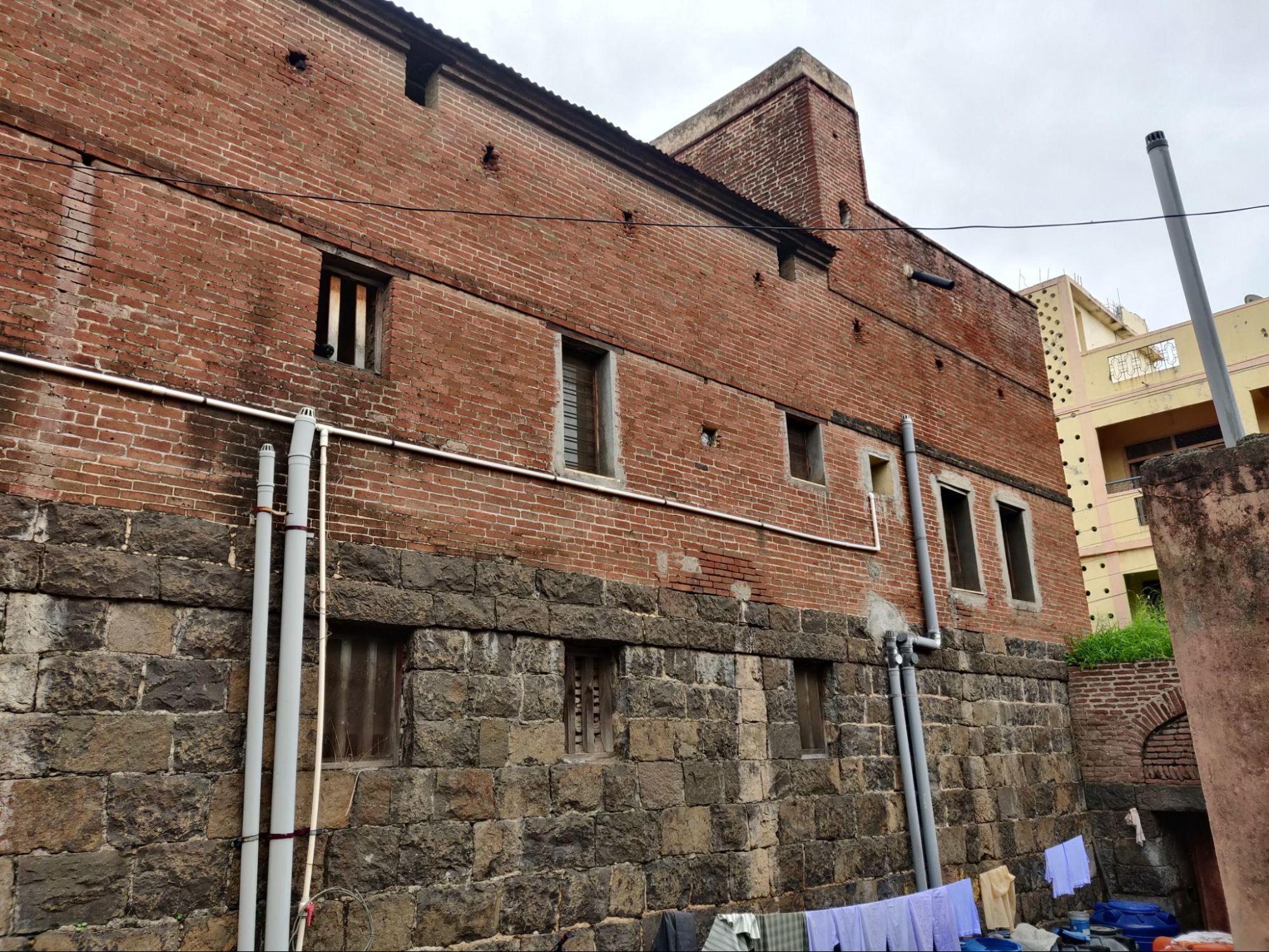 Exterior of the wada showing the striking contrast between the ground floor's black stone masonry and the upper level's exposed brick construction. (Source: CKA Archives)