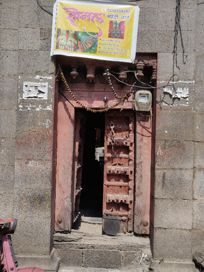 Front entrance door showing elaborate wooden carvings with traditional symbols in the 'mandap' (top ornamental section). (Source: CKA Archives)