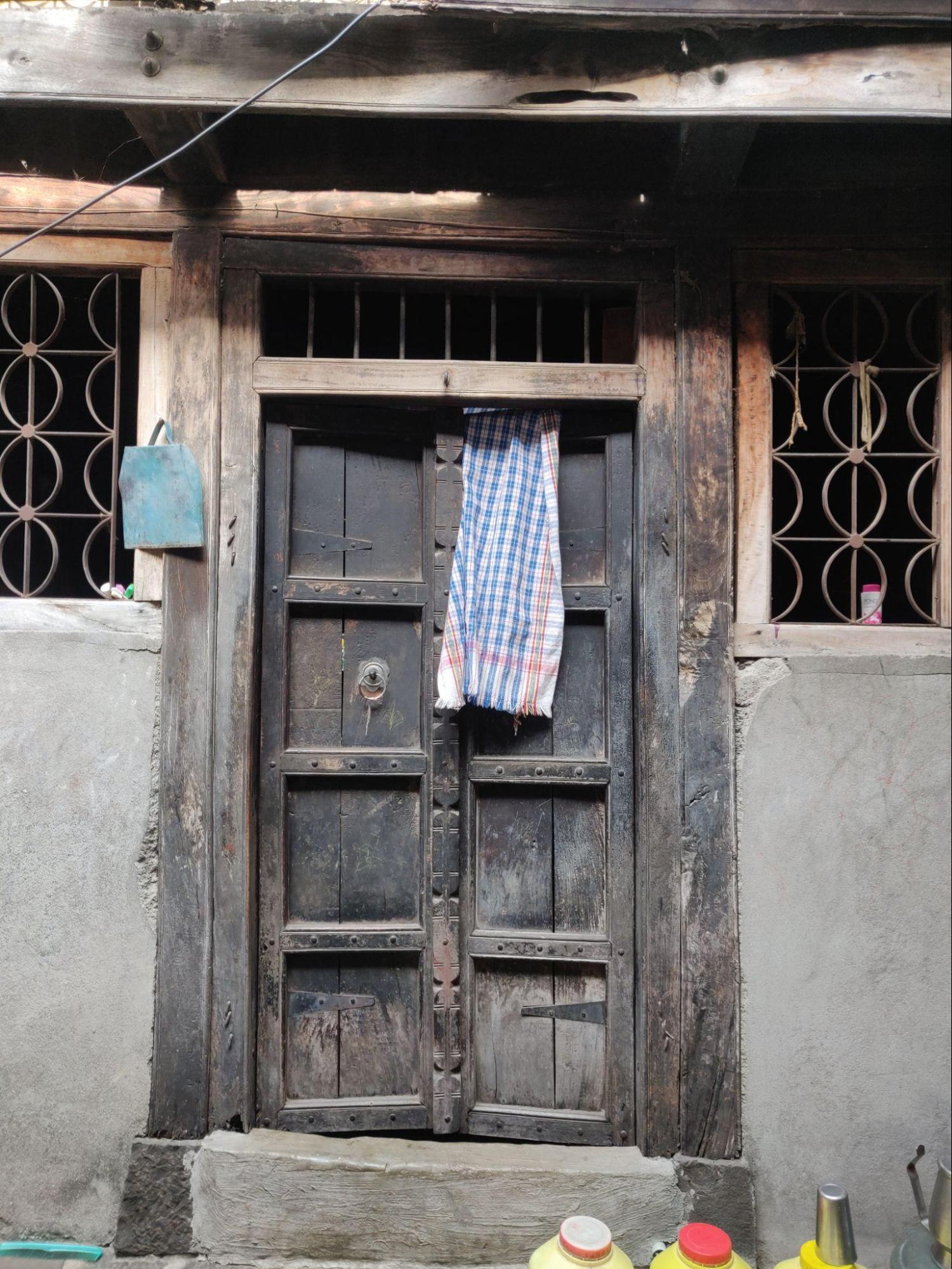 Inner courtyard door, worn and discolored, with double shutters and a panel design. (Source: CKA Archives)