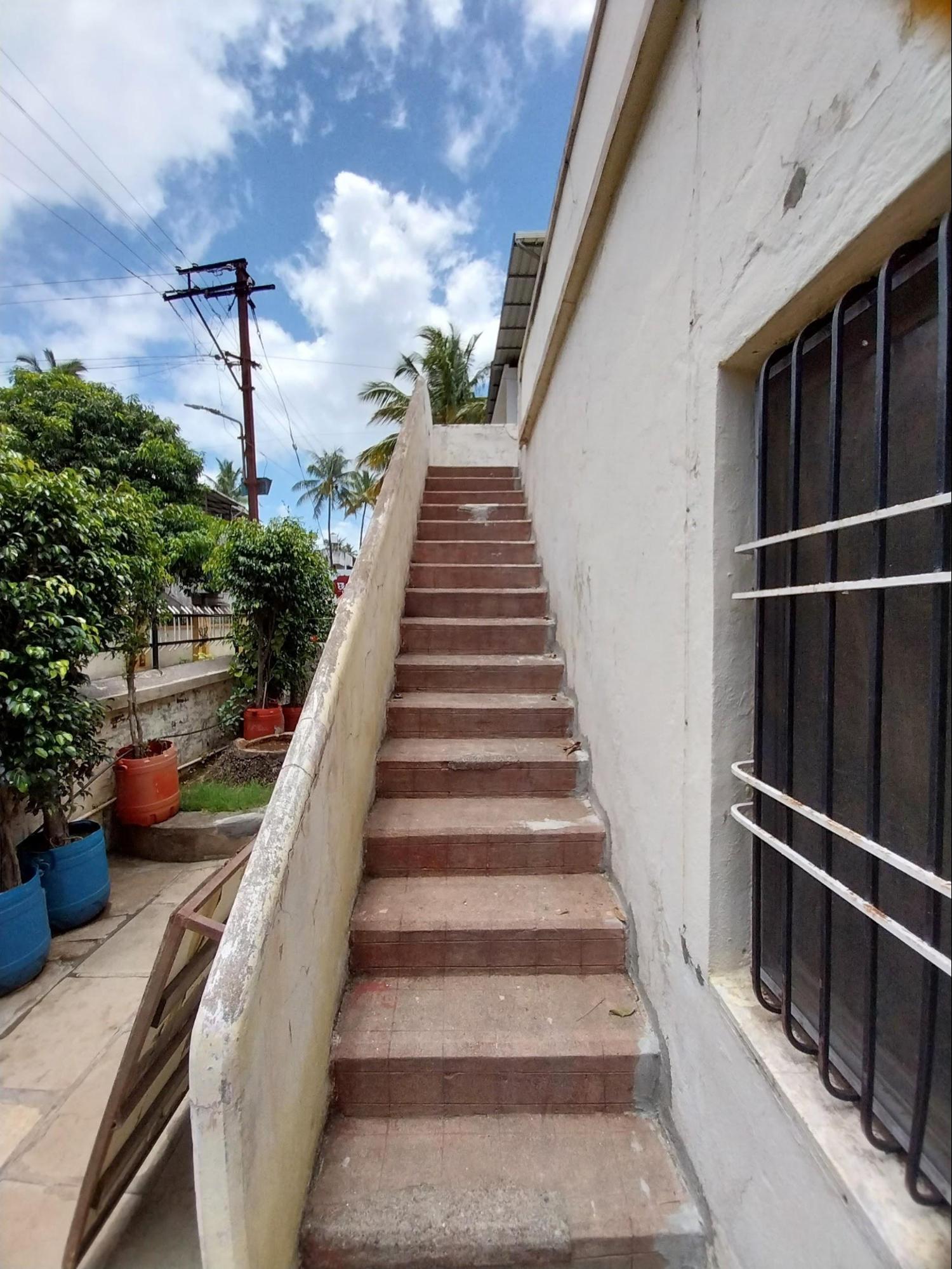 A staircase positioned against the exterior wall offers access to the terrace, connecting the ground level to the upper outdoor space. (Source: CKA Archives)