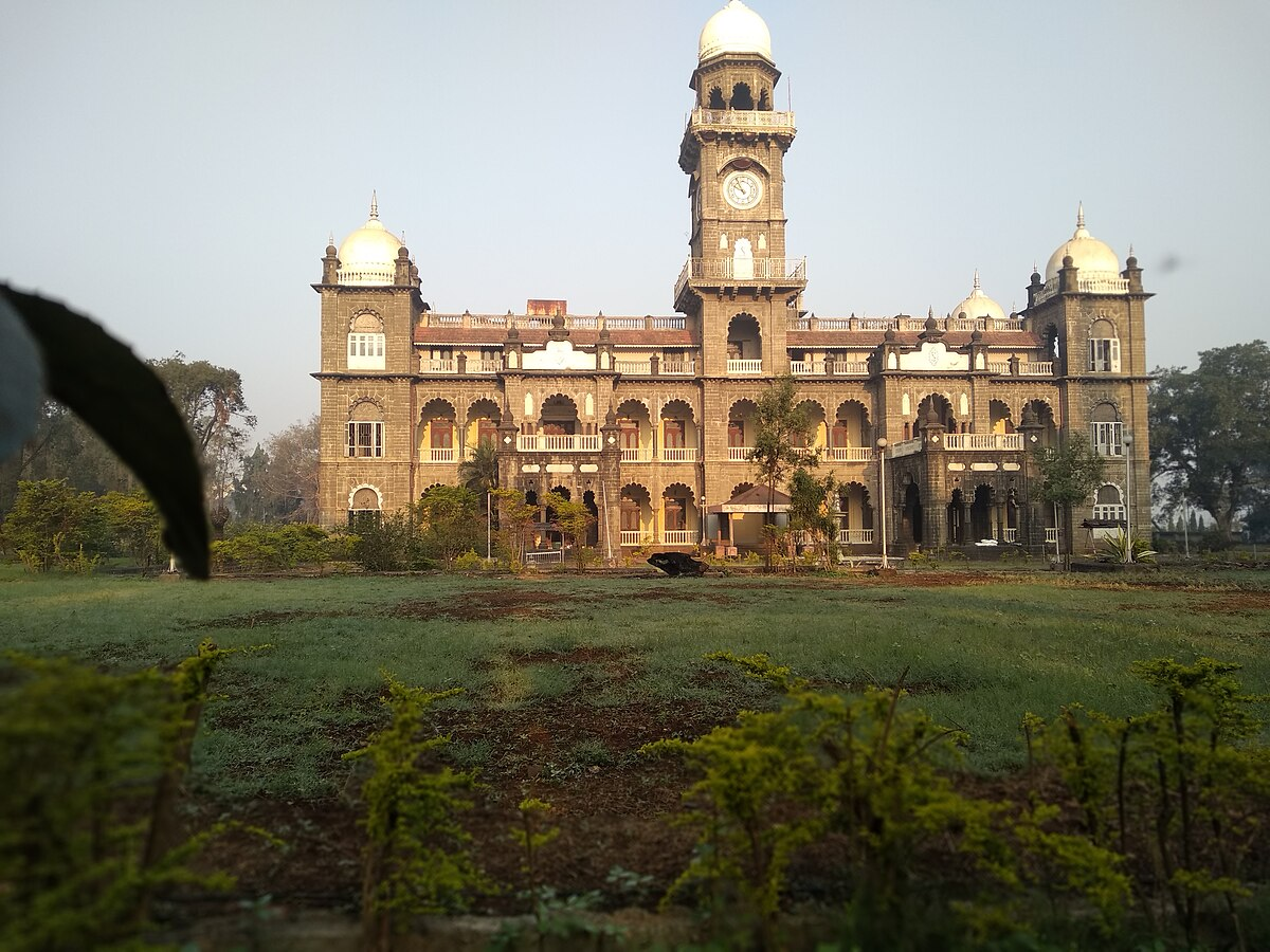 Shalini Palace’s black basalt and Italian marble facade features wide stone arches, a regal porch, and a central clock tower, reflecting Indo-Saracenic and Renaissance styles.[15]
