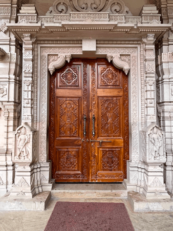 Entrance of the Balaji Mandir where the deep shade of the wooden door standing out from the white sculptures carved into the walls that surround it.(Source: CKA Archives)