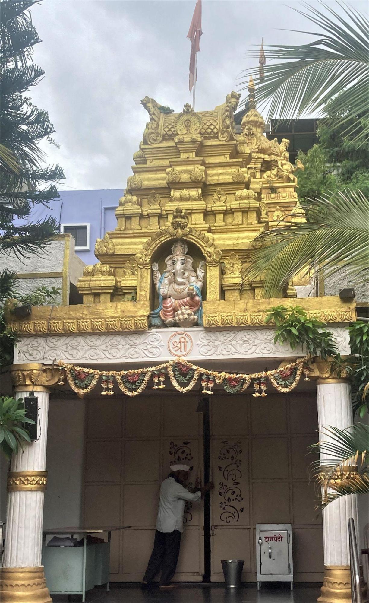 The exterior of Ashtavinayak Mandir, Latur illuminated in sunlight, with gold-toned elements highlighting the entrance. A central image of Ganesha welcomes devotees approaching the site. (Source: CKA Archives)