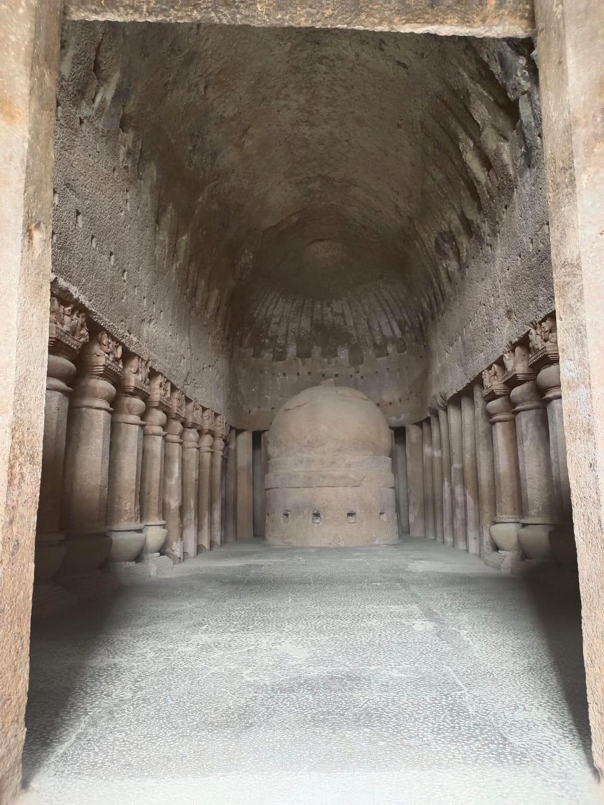 The main prayer hall (chaitya) at Kanheri, featuring a stupa at its center and flanked by intricately carved pillars. Notice the sculpted pillars inside the space, showing traces of intricate ornamental work which were carved into rock. (Source: CKA Archives)