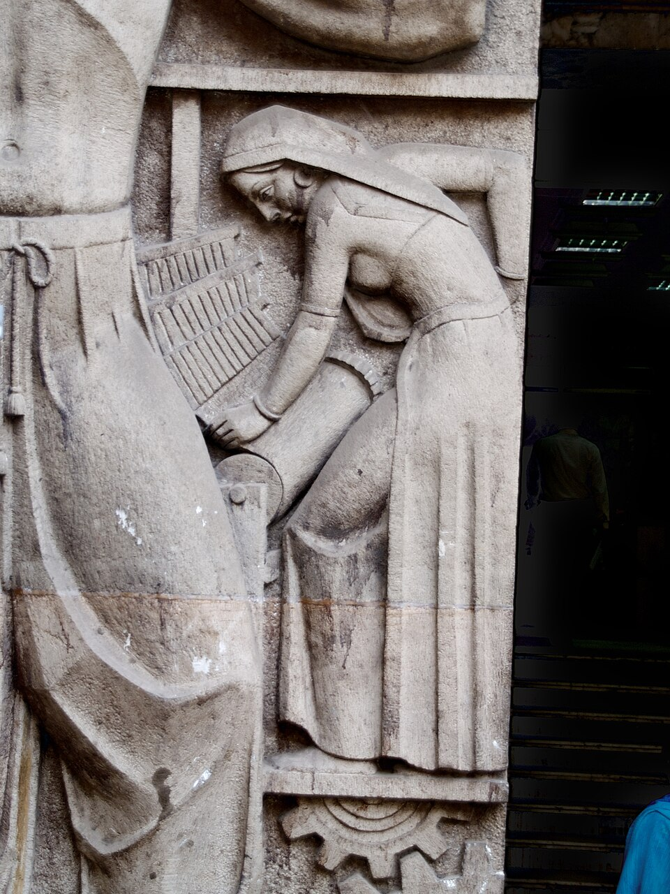 A sculptural relief on the New India Assurance Building shows a worker spinning yarn—an Art Deco representation of Bombay’s early industrial identity.[17]