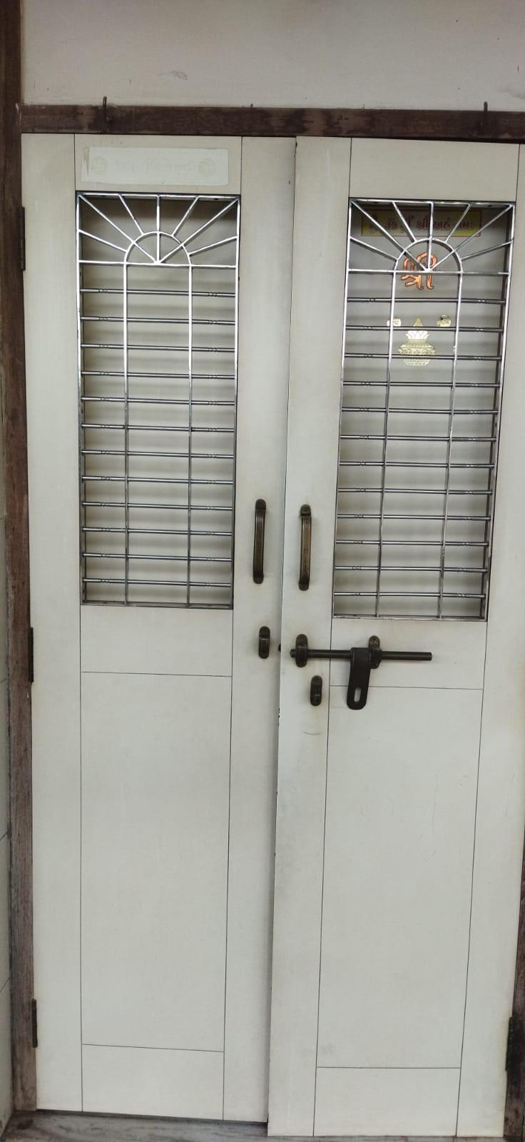 Double-shuttered apartment entrances with laminate-finished plywood doors; outer shutters include iron grills for ventilation and safety, likely added as part of later refurbishments. Source: CKA Archives