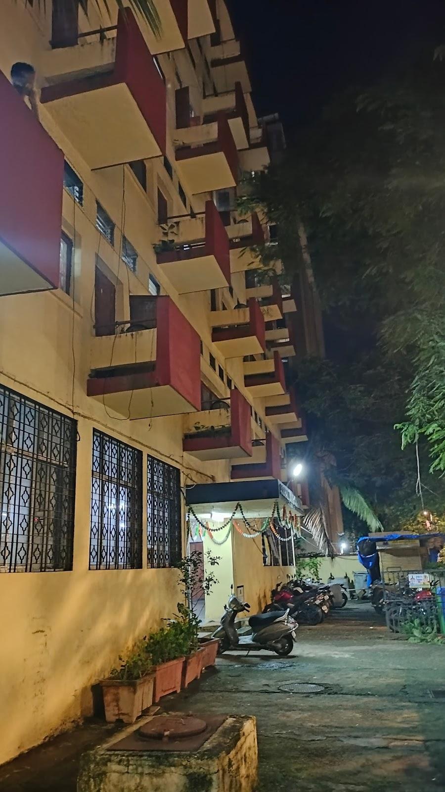 The building has an interesting and vibrant color combination with a neutral base tone and bright brick-red balconies. The lower floor has large windows with a mild metal grill and glass panes. Source: CKA Archives