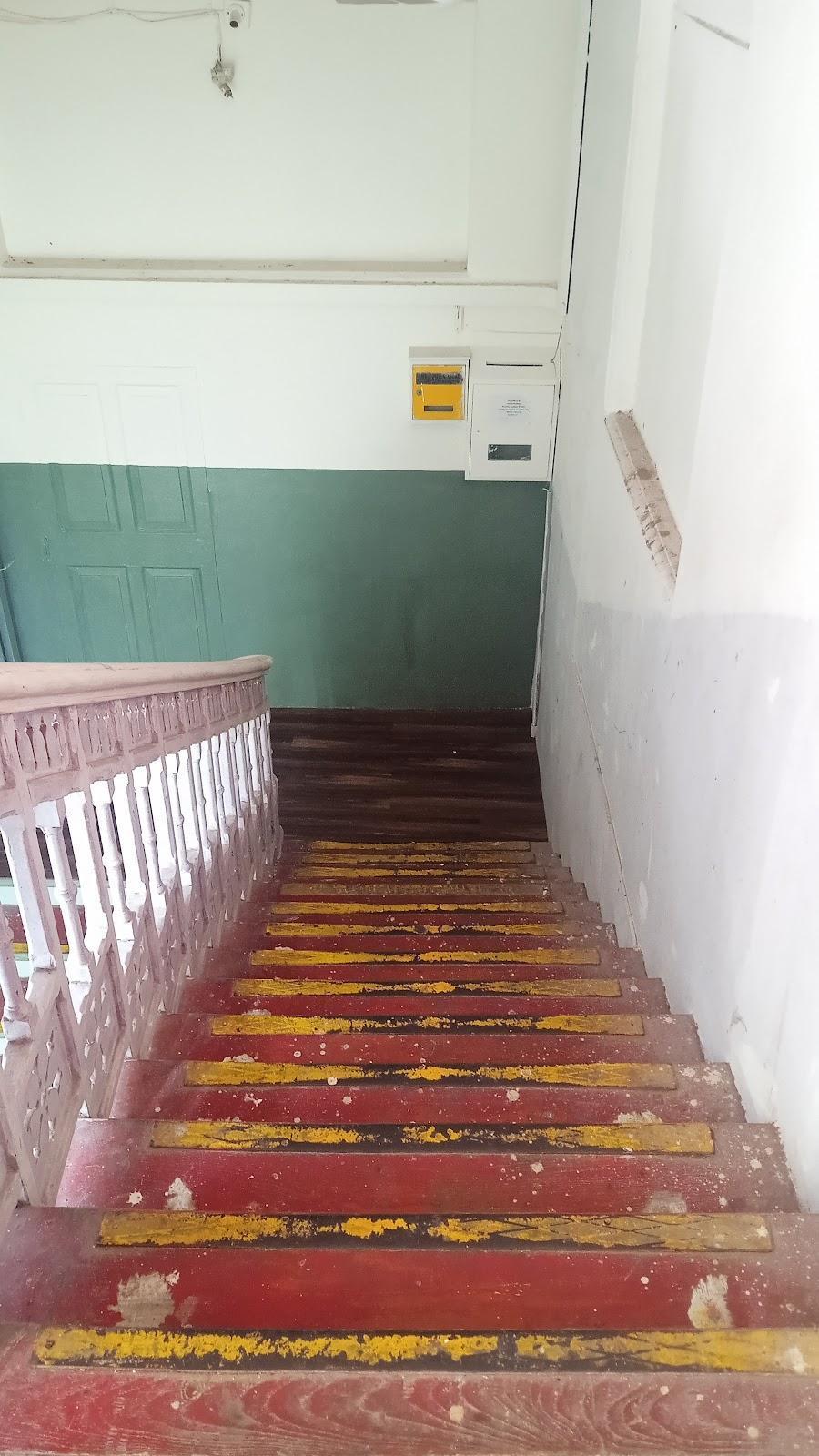 Wooden staircase in bold, contrasting yellow and red colors with a white wooden railing. Source: CKA Archives