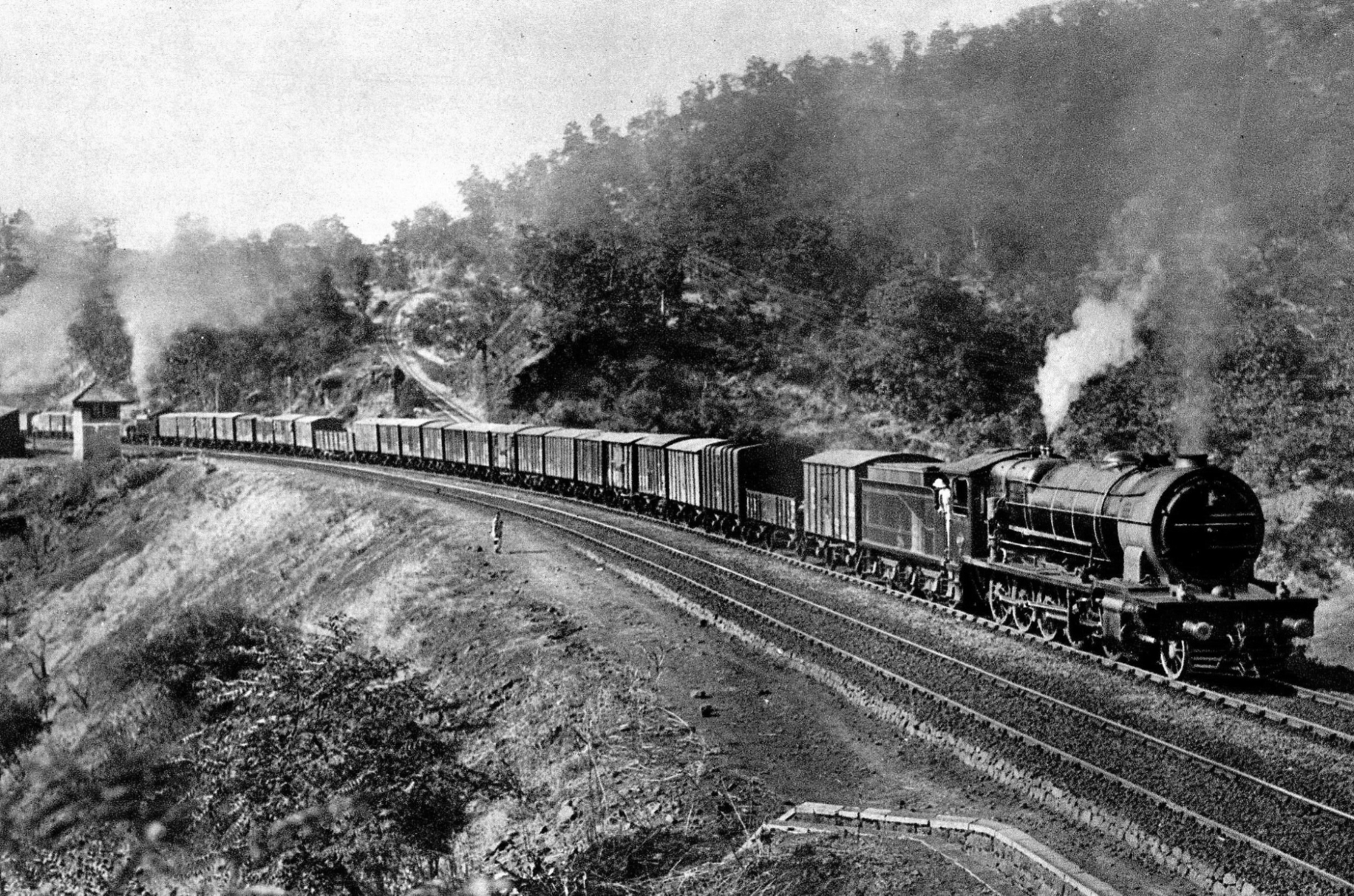 A freight train with a steam locomotive climbs the Thal Ghat.