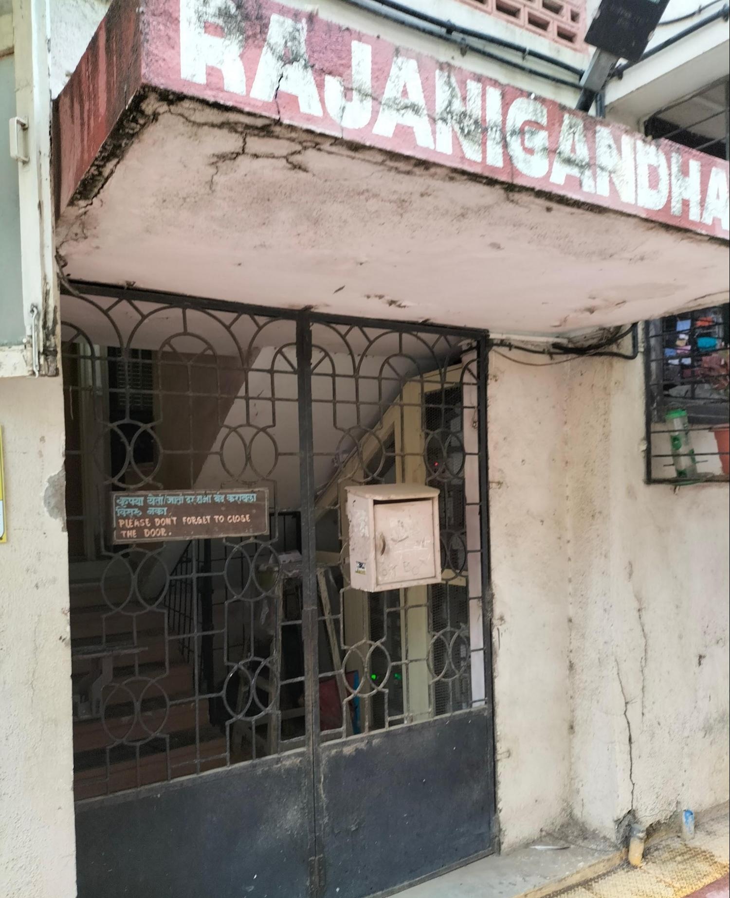 Main gate of the Rajnigandha building, which is part of the larger apartment complex. A white post box is attached to the gate, alongside a sign reminding residents to close the door. (Source: CKA Archives)