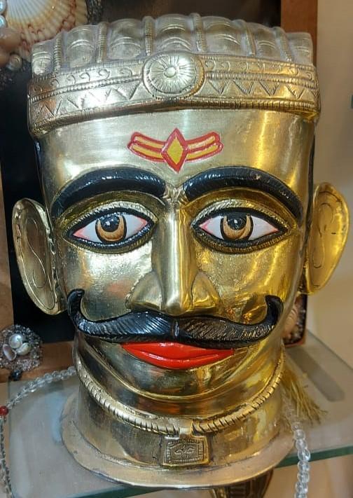Traditional metallic mask featuring detailed brass work, stylised lips, and a prominent mustache, crafted by members of the Twashta Kasar community, who have historically specialised in working with copper and brass. (Source: CKA Archives)