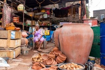 A vendor at Kumbharwada, Pune’s historic pottery market, surrounded by earthen pots, lamps, and clay items.[2]
