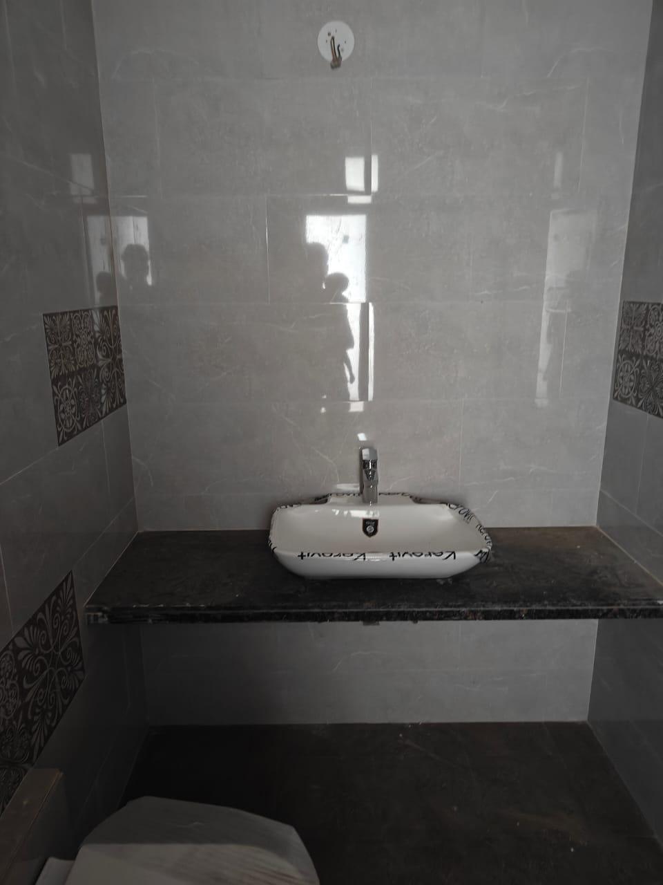 Bathroom with tiled walls and steel fixtures. The sink is set on a granite countertop. (Source: CKA Archives)