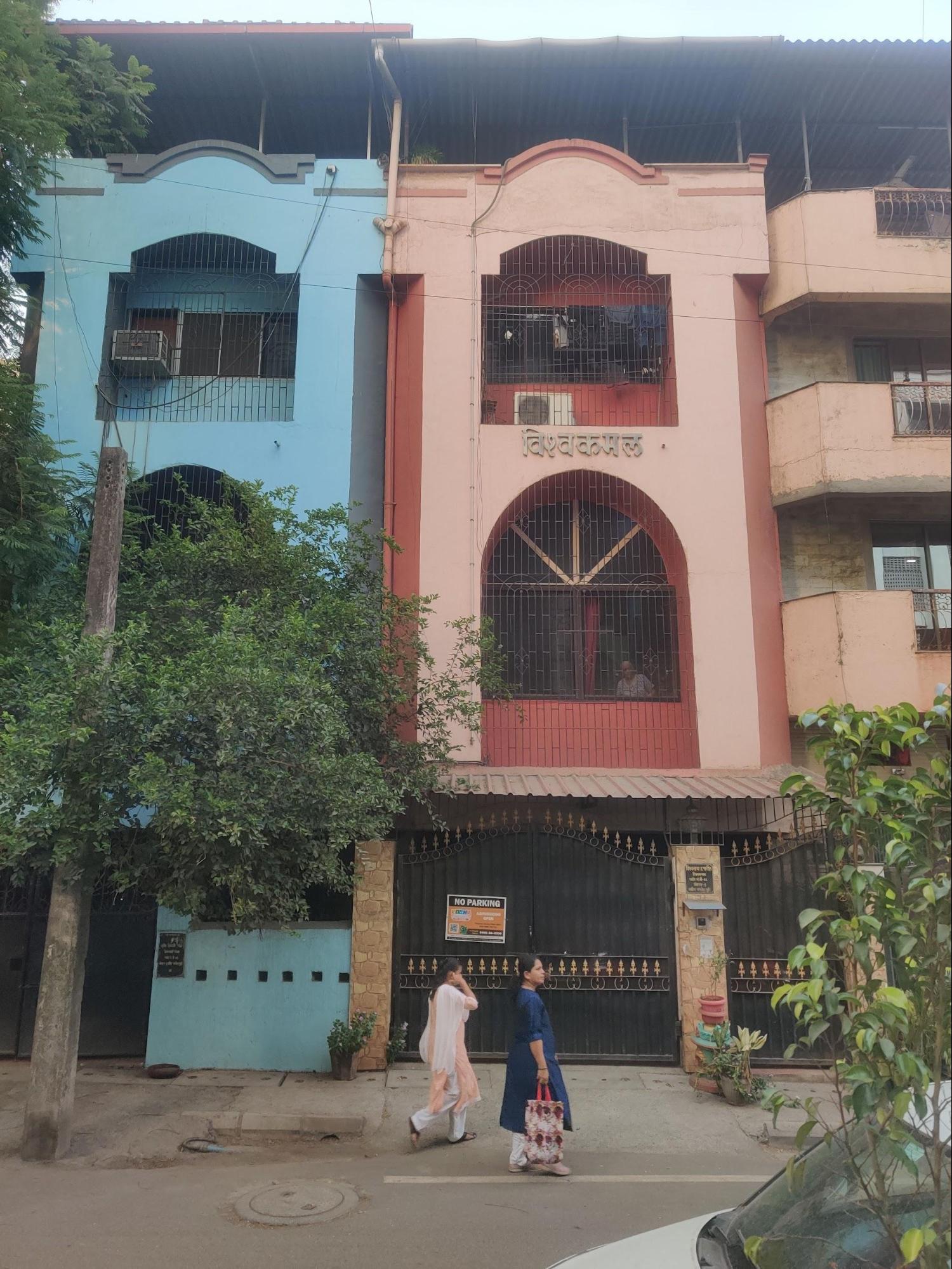 Front view of 'Vishwa-Kamal' showing its tall, narrow design with matching arches on different floors. The pink walls and dark metal details create an attractive pattern that makes this building different from its neighbors. (Source: CKA Archives)