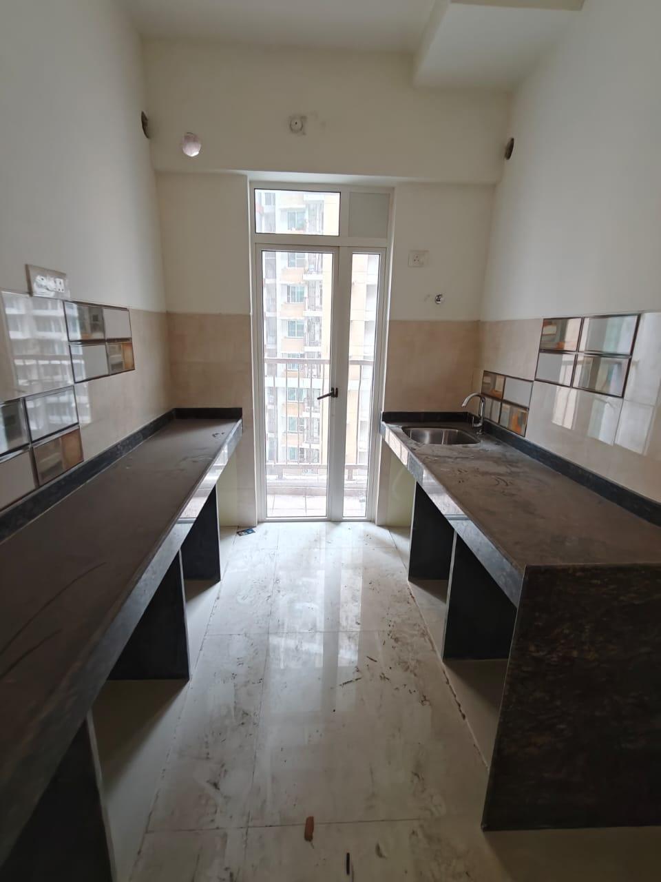 Kitchen with granite countertops on both sides and a glass door leading to a narrow balcony. (Source: CKA Archives)