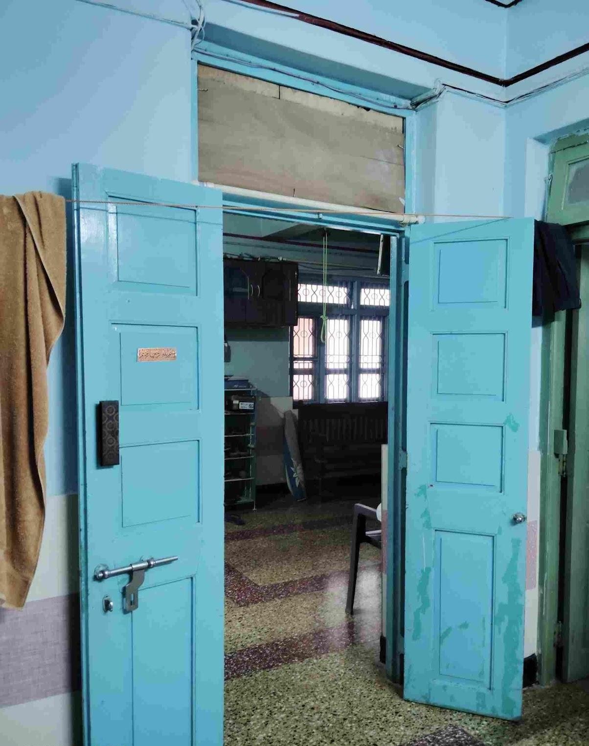 Blue-colored, wooden main entrance door of the house. Notice the upper clerestory window with a wire mesh above the door. (Source: CKA Archives)