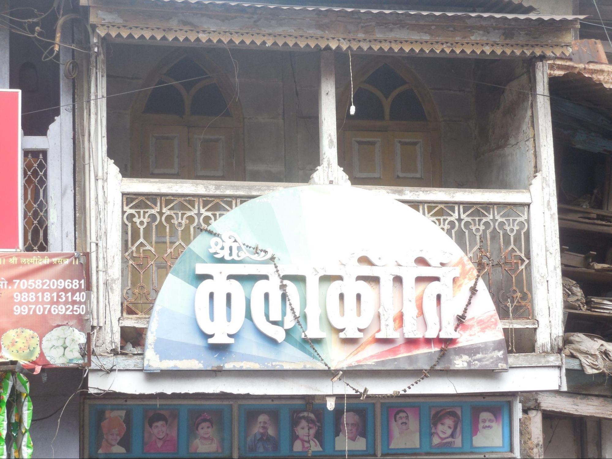 Cast iron balcony railing with timber framing. Much of the railing is concealed behind a shop hoarding.(Source: CKA Archives)
