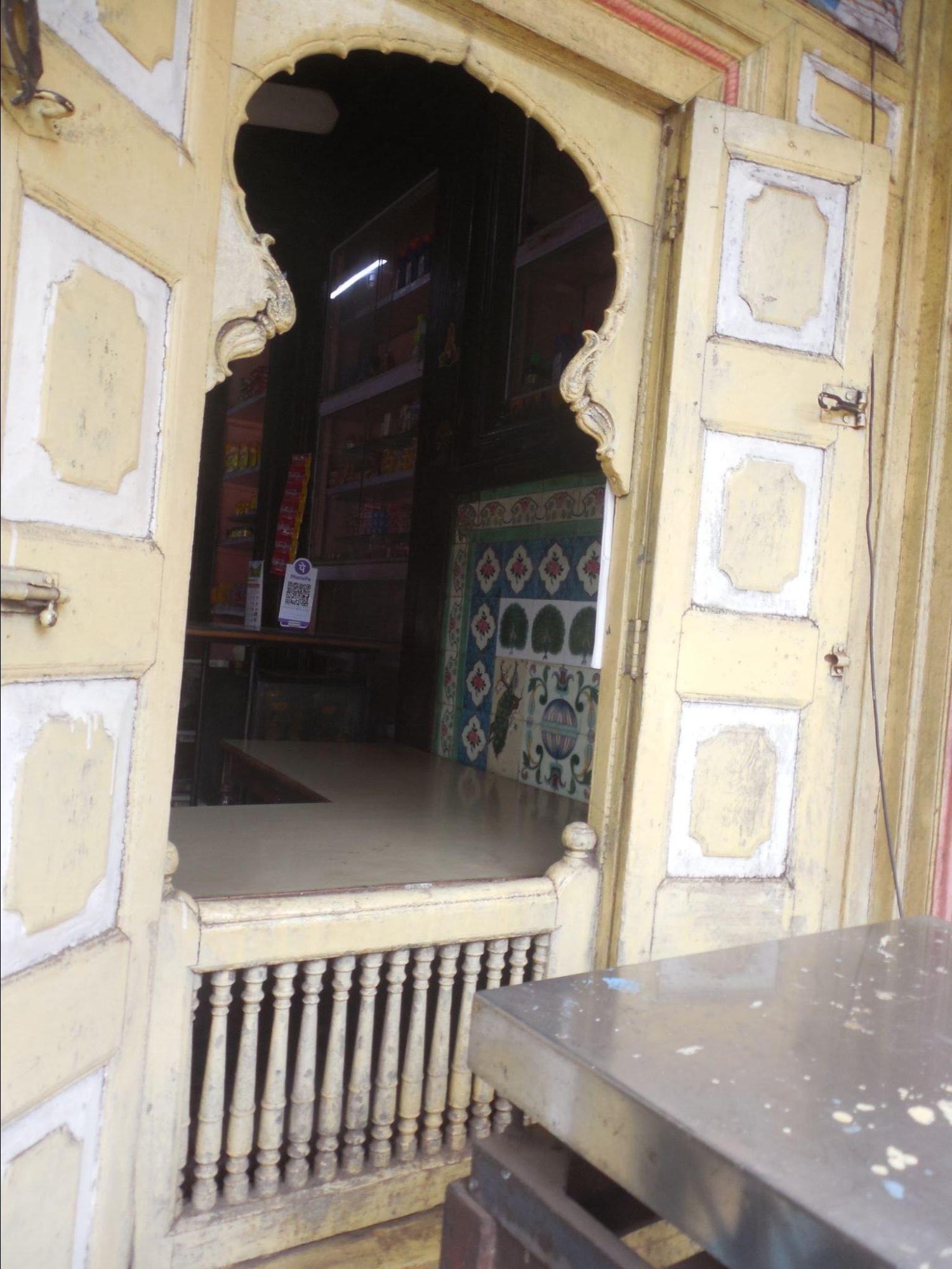 Tall, floor-length windows on the ground floor with balusters. Wooden arches above the doors show craftsmanship. Inside, a tile mosaic is visible.(Source: CKA Archives)
