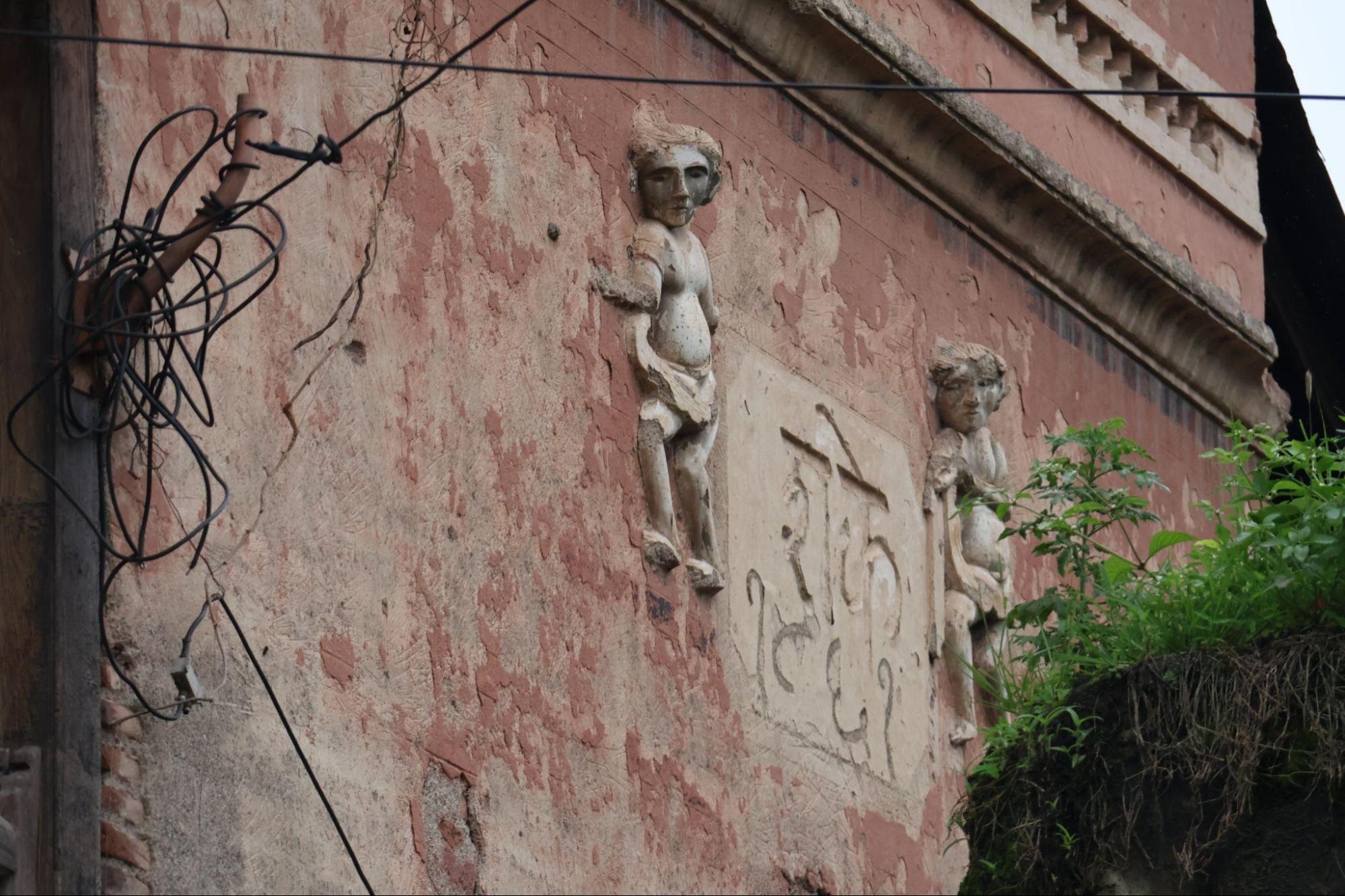 Two sculpted figures flank a carved date panel at the building’s corner. The exaggerated features and expressions suggest a protective or symbolic role, though their specific meaning is uncertain. The inscription carved here reads “Shake 1861”, corresponding to the year 1939 CE in the Gregorian calendar. This likely indicates the date of construction. Note: The Shaka calendar begins in 78 CE. To convert a Shaka year to the Gregorian calendar, 78 years are added. (Source: CKA Archives)