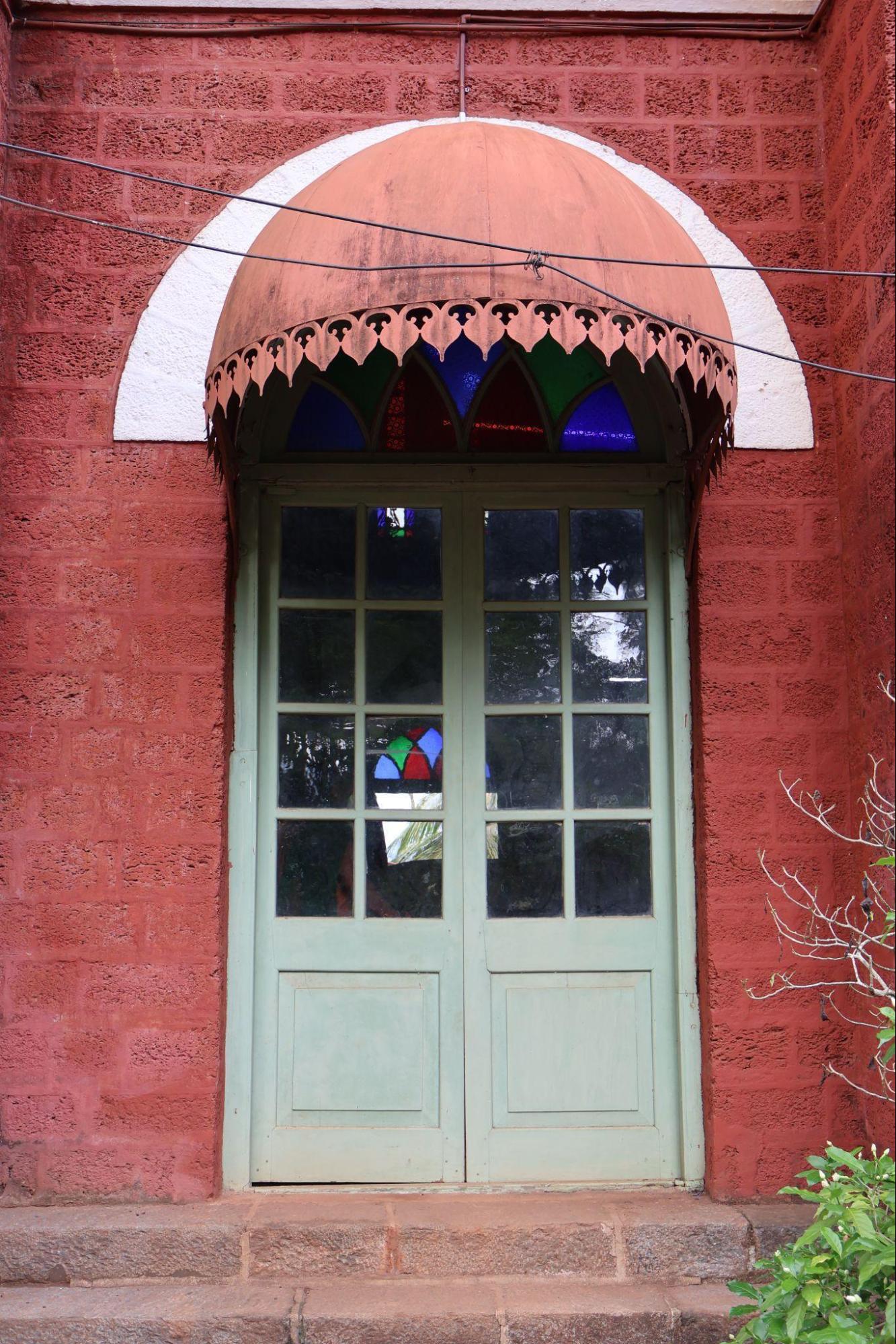 Painted in pastel green, the door is shaded by an umbrella-style overhang, featuring coloured glass and ornamental detailing. (Source: CKA Archives)