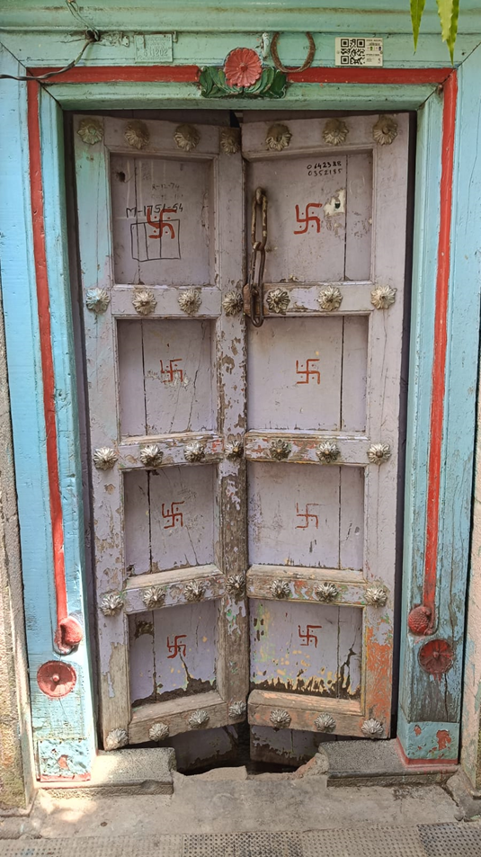 Wooden main entrance door. It is said that the ‘Swastika’ painted on the door is an auspicious symbol. The door uses a chain and padlock system for protection. (Source: CKA Archives)