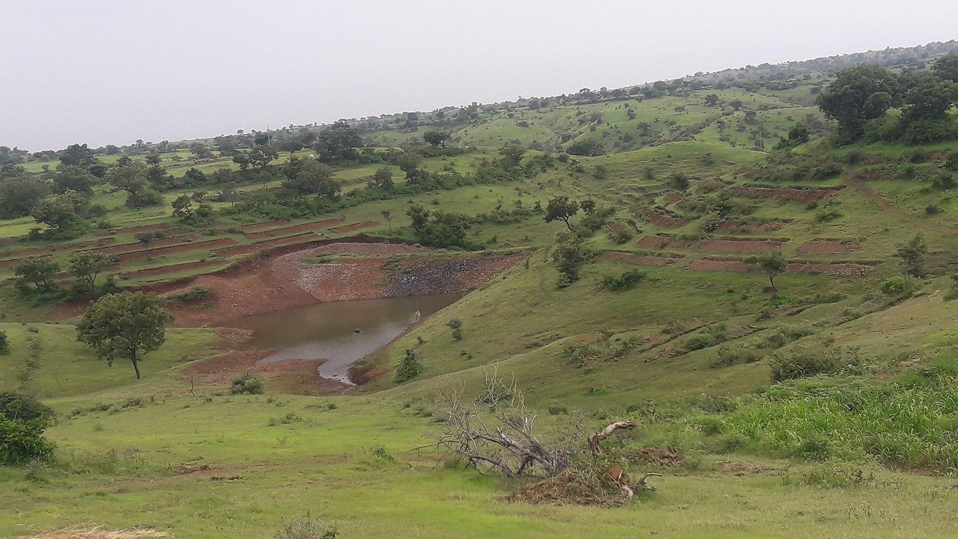 A manually made farm pond and level grooves (on the right and back)used for rainwater harvesting in the village of Mandavkhel, Beed.
