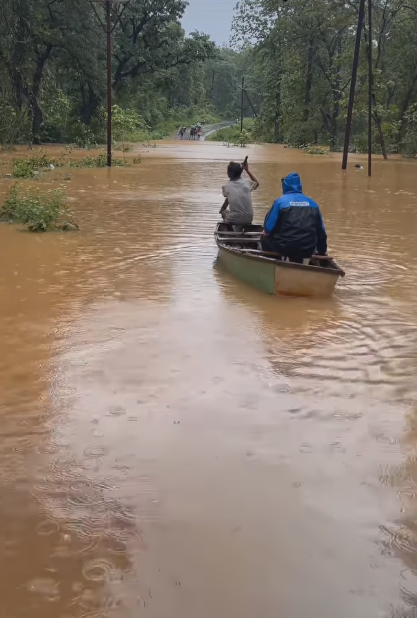 A man being ferried across a submerged road by a boatman amid rainfall.(Source: CKA Archives)